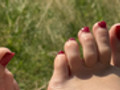 Rot lackiere FüSse im Sonnenbad