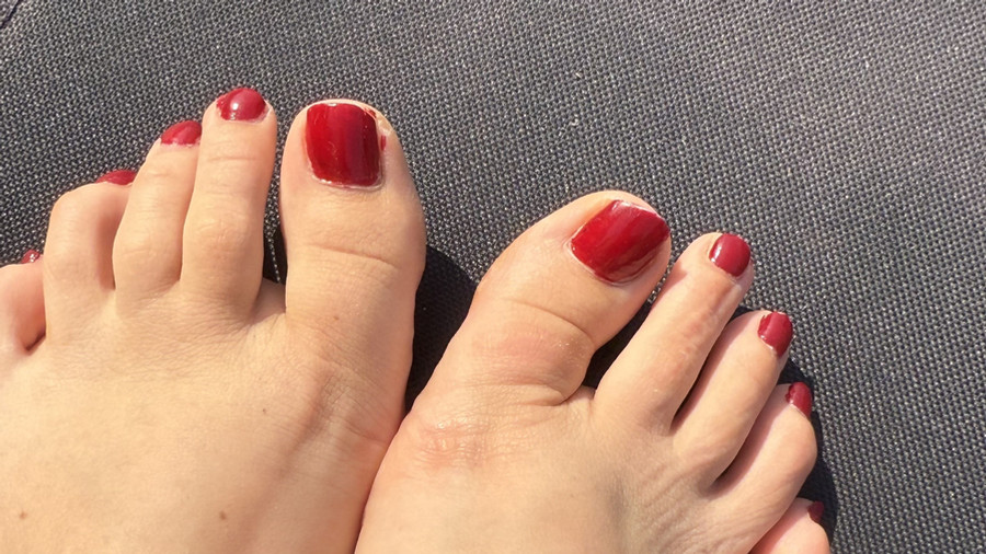 Rot lackiere FüSse im Sonnenbad